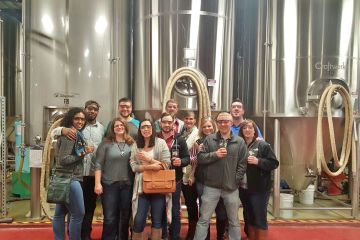 tour group standing in front of brewing barrels
