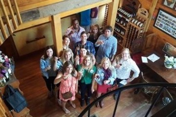 group of friends smiling at camera holding glasses